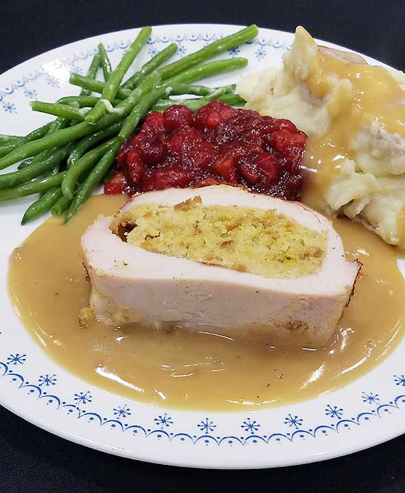 Photo of turkey plate with fresh green beans, mashed potatoes and cranberry sauce.